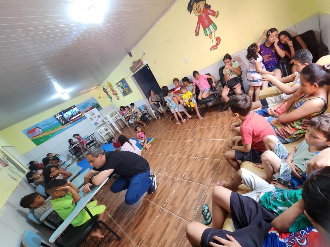 Crianças e adolescentes reunidos em uma sala de atividades do Lar Aconchego da Vó Maria